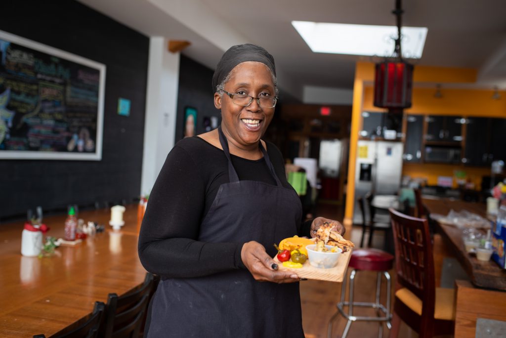 Black female restaurant owner poses with plate of food